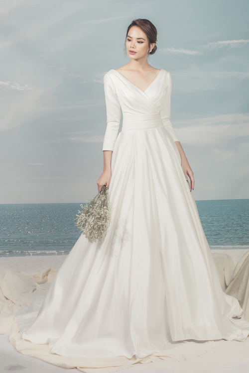 Chiếc váy mang phong cách cổ điển với phần cổ chữ V được xếp nếp khéo léo, thân váy nhấn vào vòng eo thon nhỏ của cô dâu.