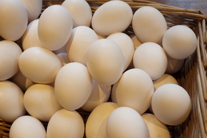 Basket filled with a pile of fresh hens eggs, close-up background.