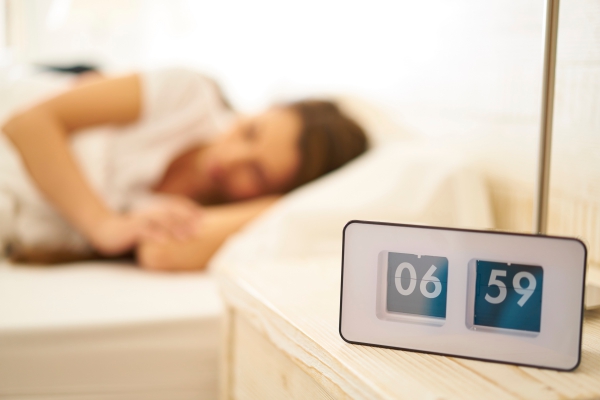 vintage clock with sleeping woman before wakeup call