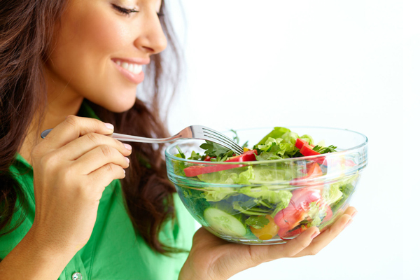 Close-up of pretty girl eating fresh vegetable salad