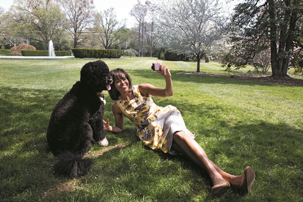 First Lady Michelle Obama takes a photograph of Bo, the Obama family dog, in the White House Kitchen Garden, April 11, 2013. (Official White House Photo by Chuck Kennedy)