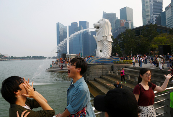 Du khách thích thú tạo dáng với tượng sư tử Merlion - Ảnh: REUTERS