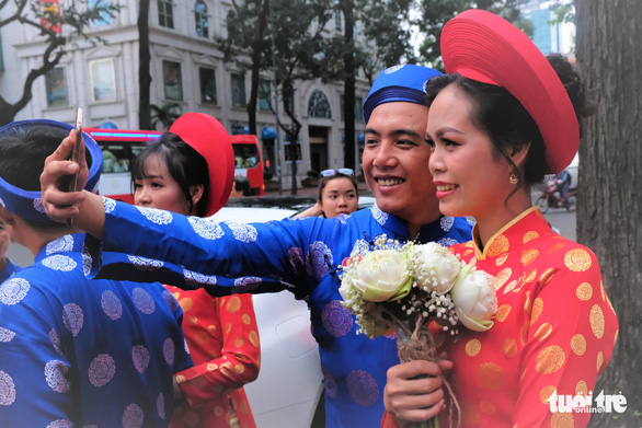Cô dâu Nguyễn Thị Mỹ Loan (27 tuổi) và chú rể Nguyễn Hoàng Minh (29 tuổi) hào hứng chụp selfie trước khi lên xe hoa - Ảnh: VŨ THỦY