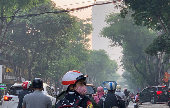 Sáng 12-11, gần như mọi người ra đường ở Hà Nội đều phải mang khẩu trang khi ô nhiễm không khí lên tới ngưỡng nguy hại; đường phố, đặc biệt khu nhà cao tầng có hiện tượng như "sương mù" đặc quánh - Ảnh: XUÂN LONG