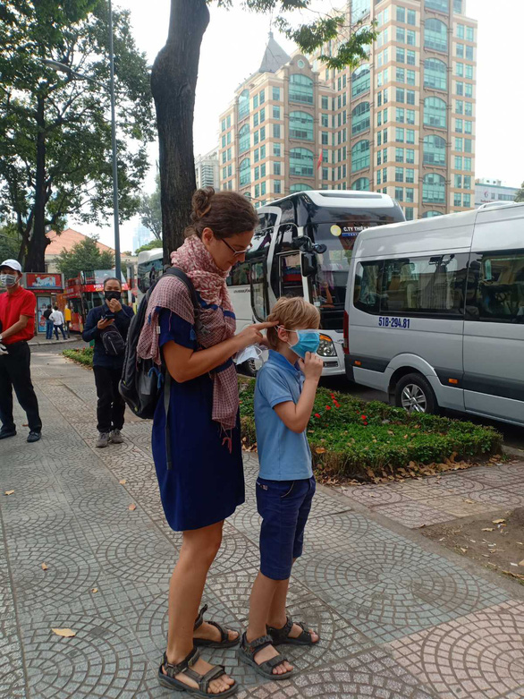 Một du khách nước ngoài vội đeo khẩu trang cho con trai ngay khi được tặng - Ảnh: N.BÌNH
