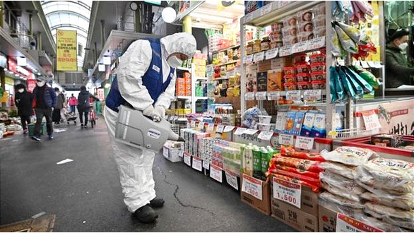 Một công nhân phun thuốc khử trùng tại một khu chợ ở Seoul - Ảnh: AFP