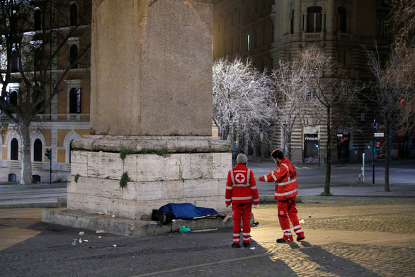 Nhân viên Hội Chữ thập đỏ ở Ý kiểm tra một người vô gia cư ở Rome - Ảnh: REUTERS