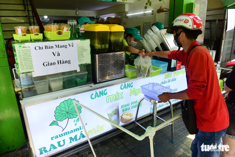 Một quán nước rau má trên đường Phan Xích Long, quận Phú Nhuận, TP.HCM lắp đặt hàng rào cách xa 2m và chỉ bán mang về - Ảnh: QUANG ĐỊNH