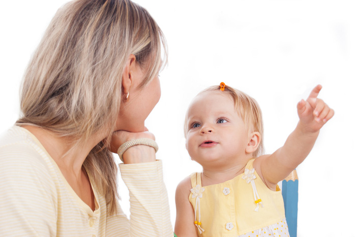 Little daughter showing to mother something isolated on white, focus on baby