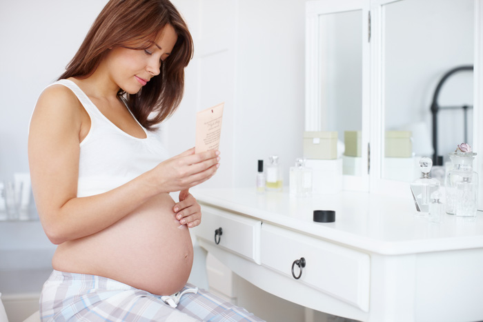 A beautiful pregnant woman rubbing skin moisturiser on her baby bump in the bathroom